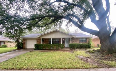 Ranch-style house with a garage, a front lawn, and covered porch | Image 1