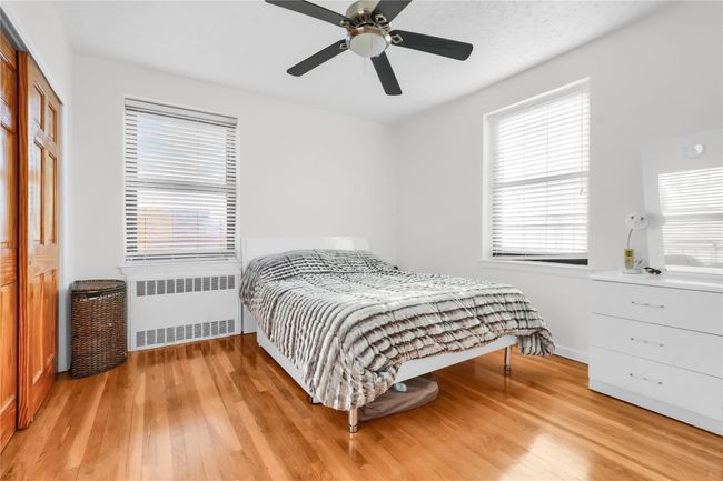 Bedroom with radiator, hardwood / wood-style floors, a ceiling fan, and a closet | Image 5
