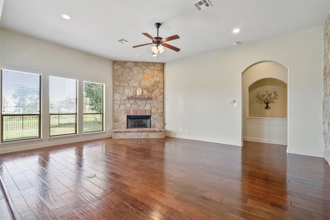 Unfurnished living room featuring wood finished floors, a ceiling fan, a fireplace, recessed lighting, and arched walkways | Image 17