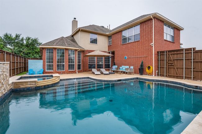 View of pool with full decking, fenced backyard, pool and hot tub! | Image 6