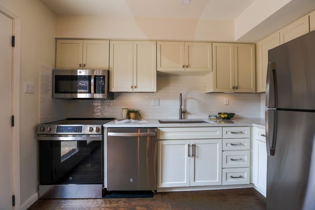 Kitchen featuring stainless steel appliances, light quartz countertops, tasteful backsplash, and engineered hardwood flooring. | Image 8