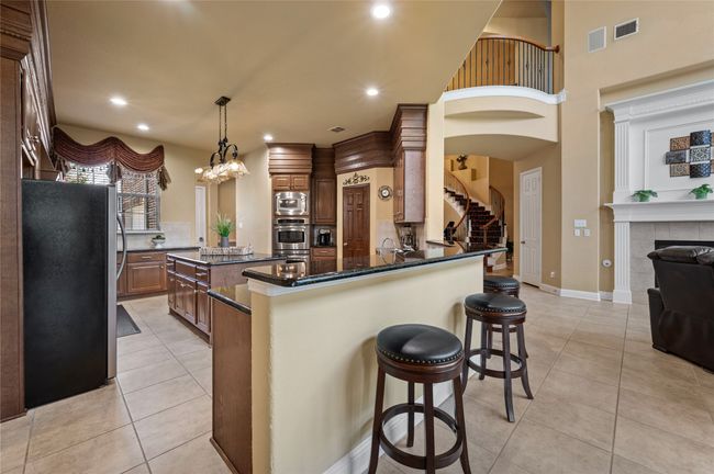 Kitchen with appliances with stainless steel finishes, a kitchen bar, light tile patterned floors, recessed lighting, and decorative light fixtures | Image 15