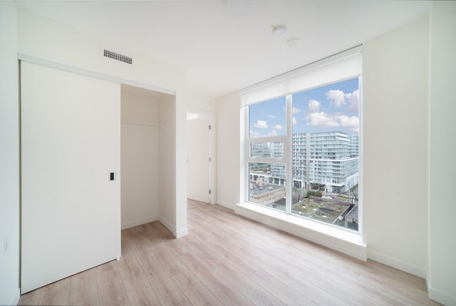 Unfurnished bedroom featuring light wood finished floors, a closet, and a view of city | Image 12