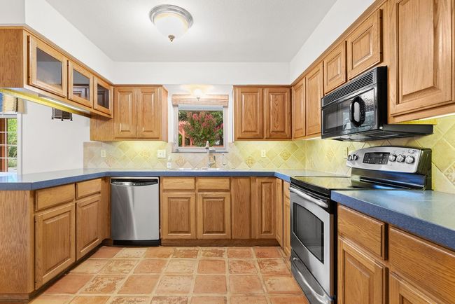Kitchen featuring appliances with stainless steel finishes, healthy amount of natural light, dark countertops, and glass insert cabinets | Image 4