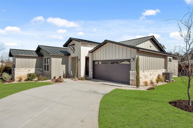 Modern inspired farmhouse featuring stone siding, concrete driveway, an attached garage, board and batten siding, and a front yard | Image 29
