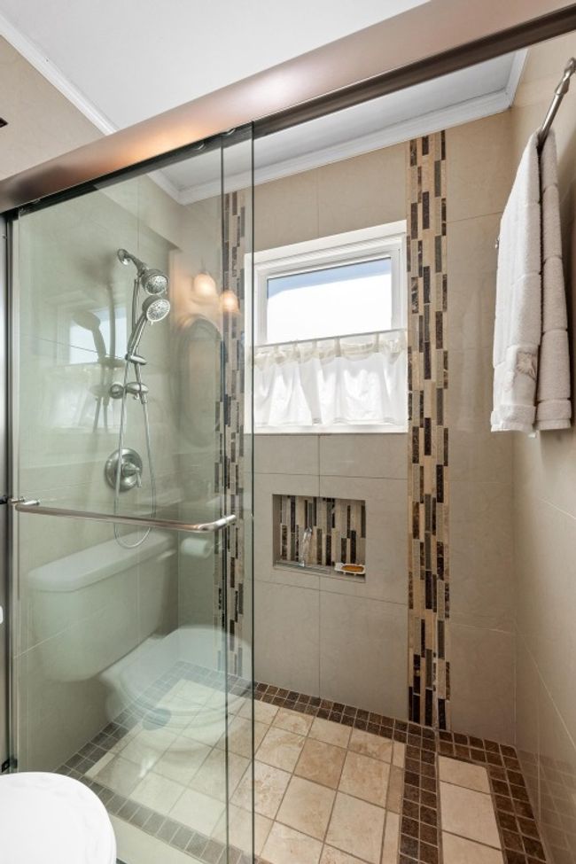 Bathroom featuring a tile shower, crown molding, and toilet | Image 20
