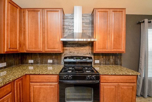The kitchen features a gas oven and stainless steel vent hood. | Image 11