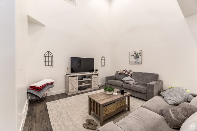 Living area with wood finished floors, a high ceiling, and baseboards | Image 6