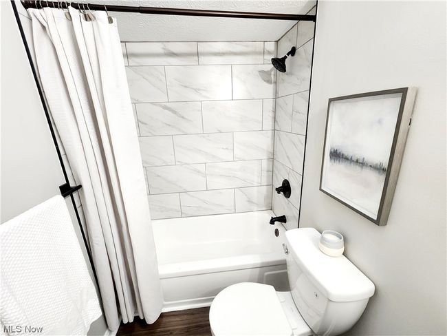 Bathroom featuring shower / bathtub combination with curtain, toilet, and hardwood / wood-style flooring | Image 19