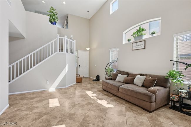 Living room featuring a towering ceiling, stairway, baseboards, and tile patterned flooring | Image 11