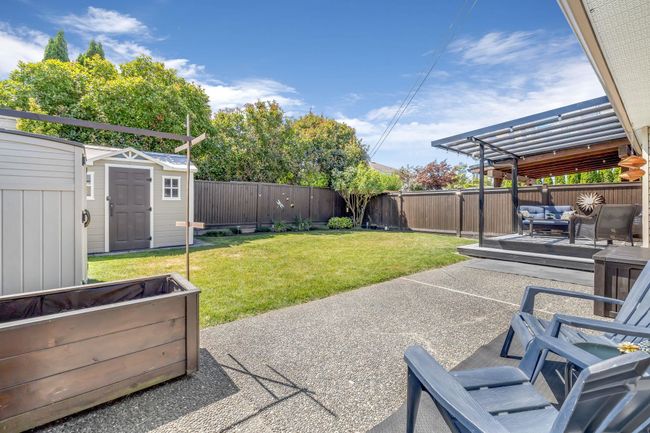 View of yard featuring a patio area, an outdoor structure, a fenced backyard, and a storage shed | Image 27