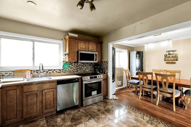 Kitchen featuring appliances with stainless steel finishes, a sink, backsplash, ornamental molding, and pendant lighting | Image 5