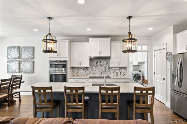 Kitchen with hanging light fixtures, stainless steel appliances, dark hardwood / wood-style floors, and washer / clothes dryer | Image 12