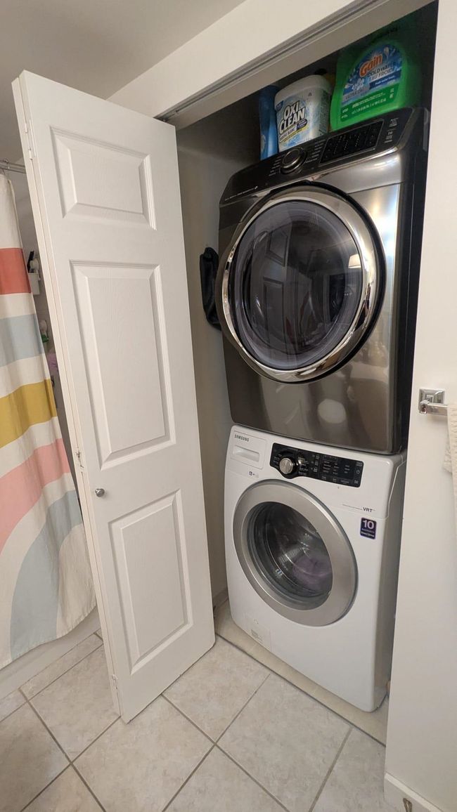Clothes washing area featuring light tile patterned floors, stacked washer and clothes dryer, and laundry area | Image 20