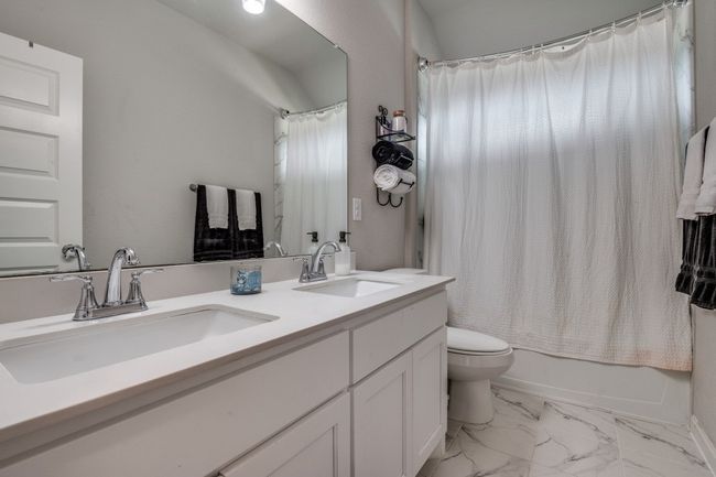 Full bath with double vanity, marble look tiles, and shower / bath combo | Image 20