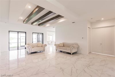 Living room with beamed ceiling, a tray ceiling, and light tile floors | Image 2