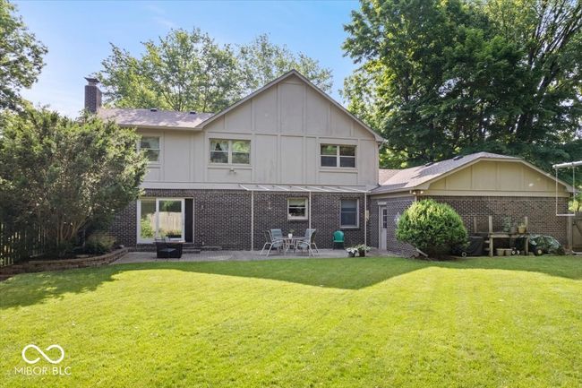 back of house with a patio, a lawn, a chimney, brick siding, and board and batten siding | Image 38