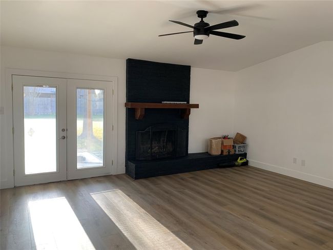 Unfurnished living room with french doors, wood finished floors, ceiling fan, and a brick fireplace | Image 9