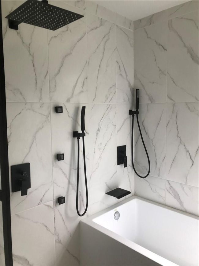 Bathroom featuring tiled shower / bath combo and tile walls | Image 6