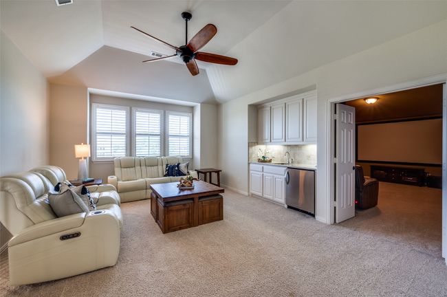 The second-floor game room is a versatile space, featuring three large windows with plantation shutters, a ceiling fan for comfort, and a convenient wet bar for added entertainment. | Image 26