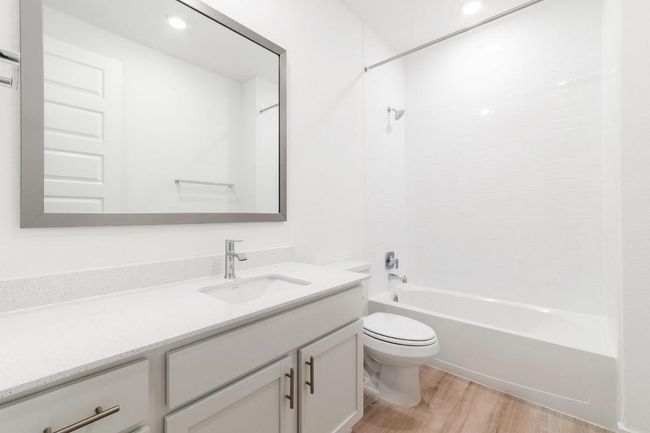 Full bath with wood finished floors, toilet, vanity, bathing tub / shower combination, and recessed lighting | Image 19