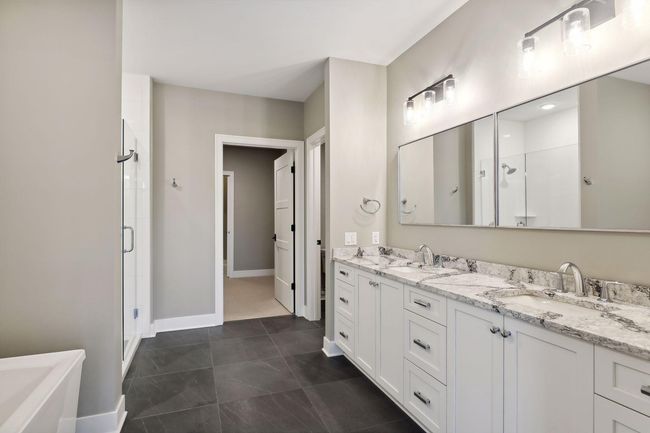 Spa-like primary bath with heated floors, dual sinks, separate tub and shower, plus ample storage space | Image 10