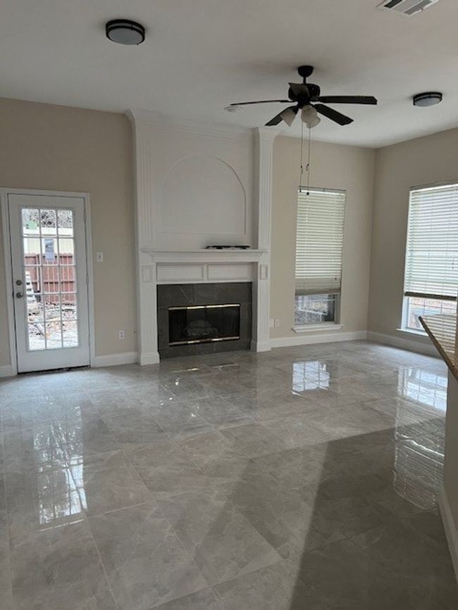 Unfurnished living room featuring healthy amount of natural light, ceiling fan, a fireplace, and baseboards | Image 9