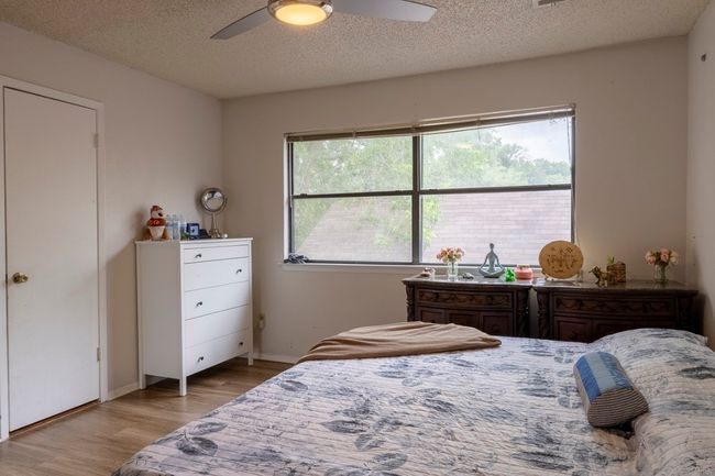 Bedroom with wood finished floors, a textured ceiling, baseboards, and a ceiling fan | Image 22