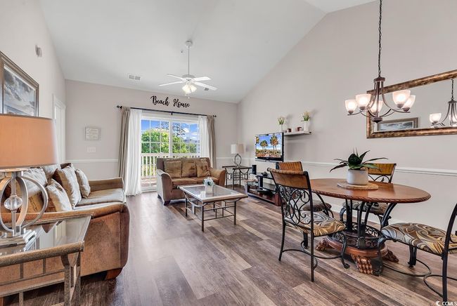 Dining space with baseboards, visible vents, high vaulted ceiling, ceiling fan with notable chandelier, and wood finished floors | Image 8