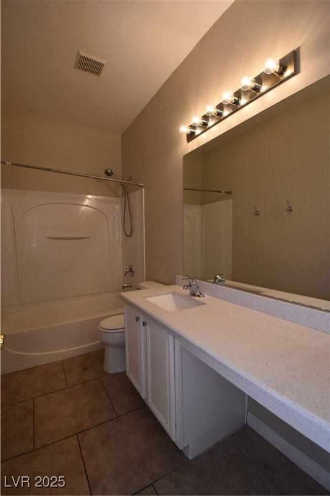 Bathroom with tile patterned floors, visible vents, toilet, vanity, and shower / tub combination | Image 14