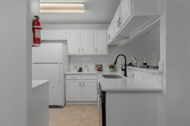 Kitchen featuring white cabinetry, a sink, light countertops, and freestanding refrigerator | Image 18