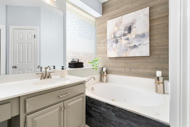 Full bath featuring vanity, a jetted tub, and wooden walls | Image 18