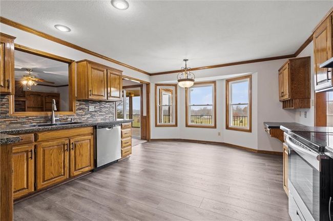 Kitchen featuring decorative backsplash, white range with electric stovetop, sink, wood-type flooring, and dishwasher | Image 14