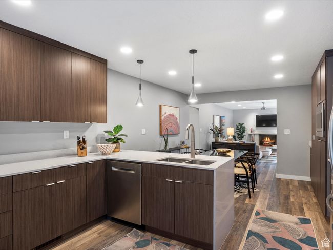 Kitchen featuring stainless steel dishwasher, a peninsula, open floor plan, dark wood-style flooring, and light countertops | Image 12