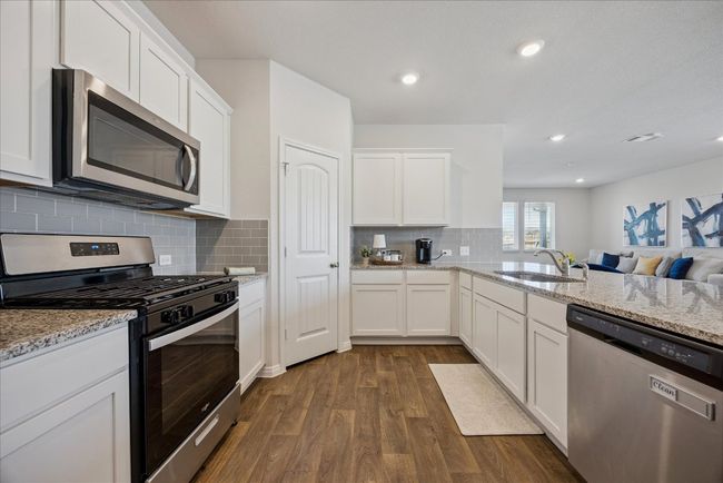 Kitchen featuring stainless steel appliances, dark wood-style floors, recessed lighting, white cabinets, and decorative backsplash | Image 20
