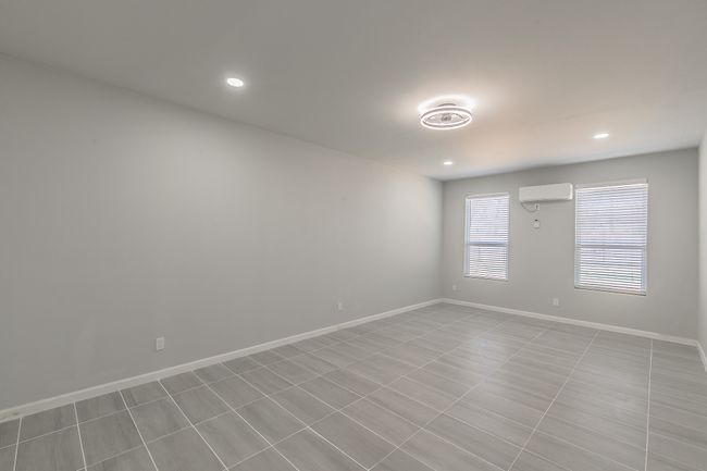 Empty room featuring baseboards, a wall unit AC, and recessed lighting | Image 7
