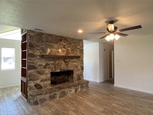Wood-burning fireplace has shelving for storage on each side | Image 5
