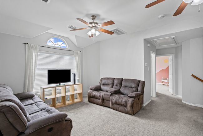 Carpeted living area with attic access, ceiling fan, and vaulted ceiling | Image 25