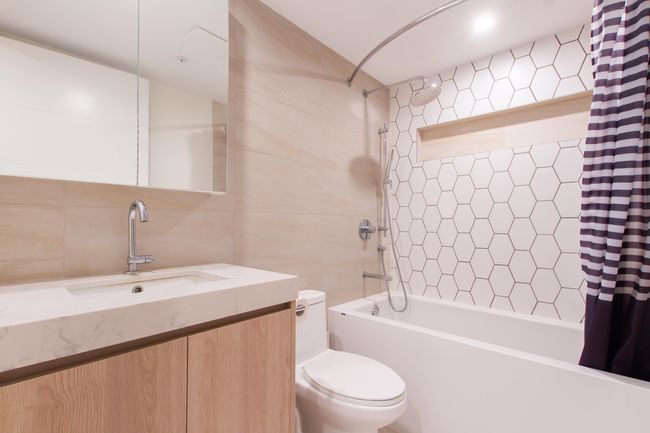 Full bath featuring shower / tub combo, tile walls, toilet, and vanity | Image 12