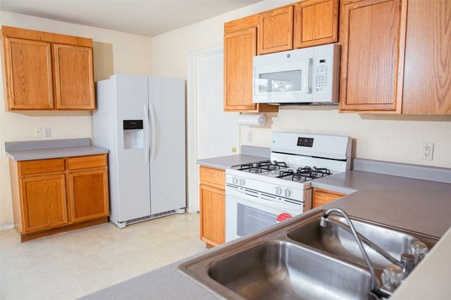 Kitchen featuring white appliances, a sink, light countertops, and brown cabinetry | Image 8
