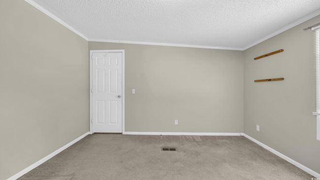 Carpeted empty room with crown molding and a textured ceiling | Image 14