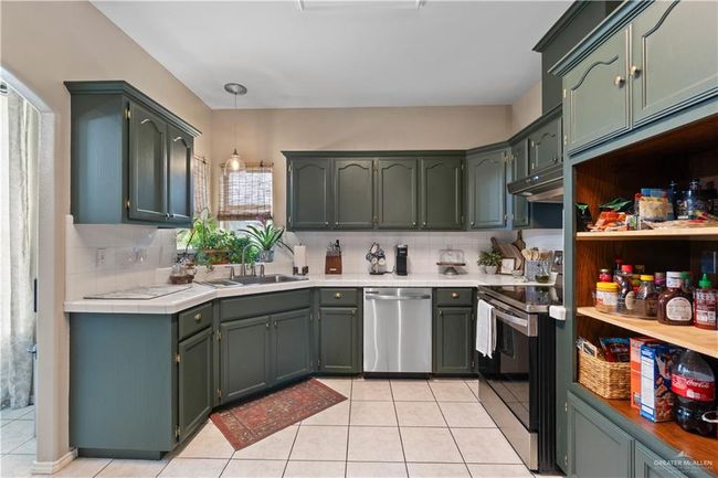 Kitchen with stainless steel appliances, a sink, tasteful backsplash, light tile patterned floors, and decorative light fixtures | Image 12