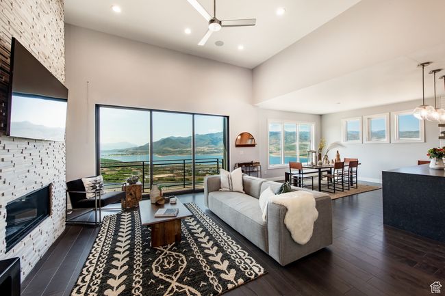 Living room with a fireplace, a towering ceiling, ceiling fan, and dark wood-type flooring | Image 14