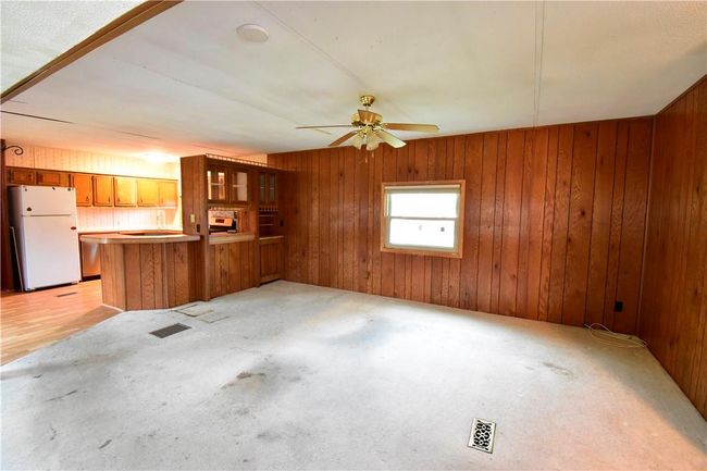 Unfurnished living room featuring wooden walls, ceiling fan, and light colored carpet | Image 26