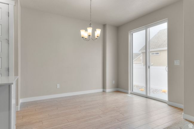 Unfurnished dining area featuring baseboards, a notable chandelier, and light wood-style floors | Image 14