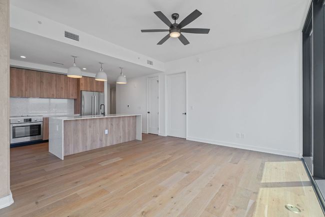 Kitchen featuring stainless steel appliances, modern cabinets, light countertops, brown cabinetry, and light wood-style flooring | Image 5