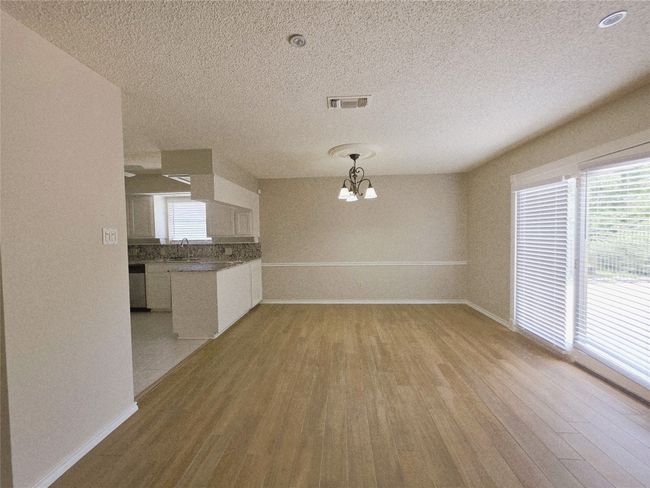 Unfurnished living room featuring a textured ceiling, baseboards, wood finished floors, a fireplace with raised hearth, and built in features | Image 12