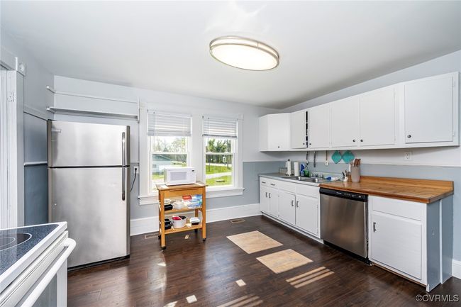Kitchen with dark wood finished floors, white cabinets, dishwasher, light countertops, and a sink | Image 14