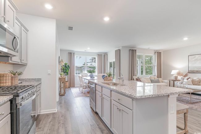 Kitchen featuring sink, a breakfast bar, appliances with stainless steel finishes, a center island with sink, and light wood-type flooring | Image 4