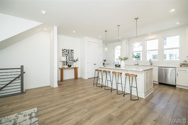 Kitchen featuring a kitchen bar, a center island, light wood-style floors, recessed lighting, and white cabinetry | Image 10